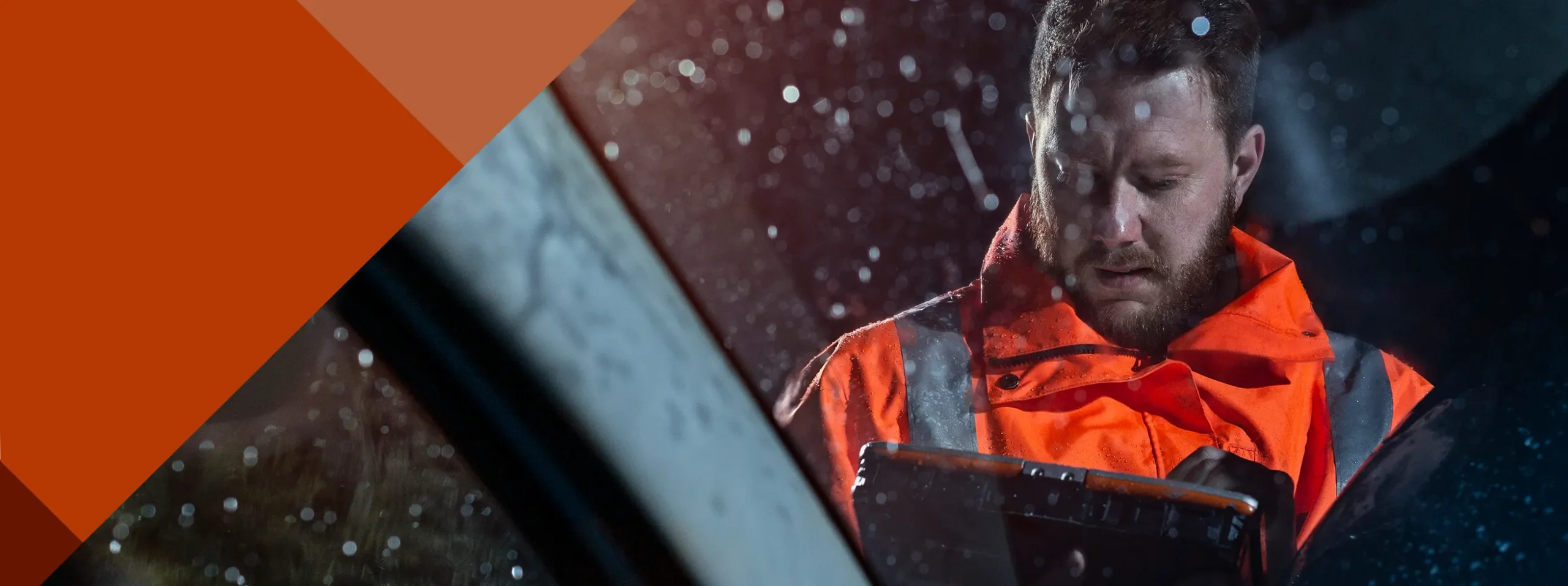 RAC patrol member standing in the rain outside a car, checking his inspection tablet
