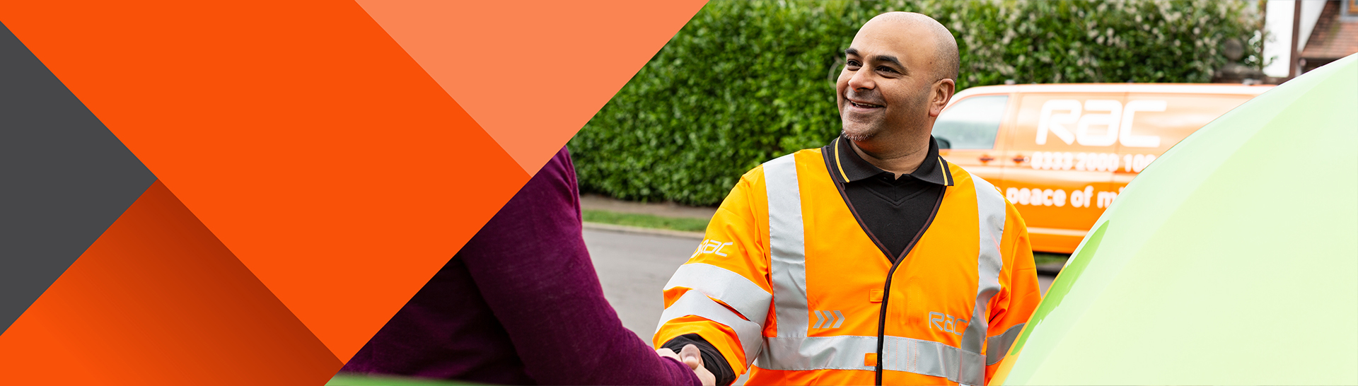 RAC patrol member in an orange uniform smiling and shaking hands with a driver beside a broken-down car